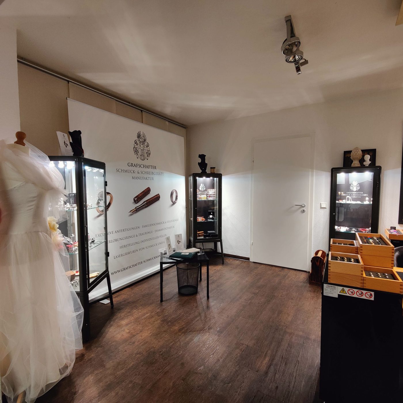 Ausstellungsraum mit Brautkleid und Vitrinen für Trauringe und Schmuck