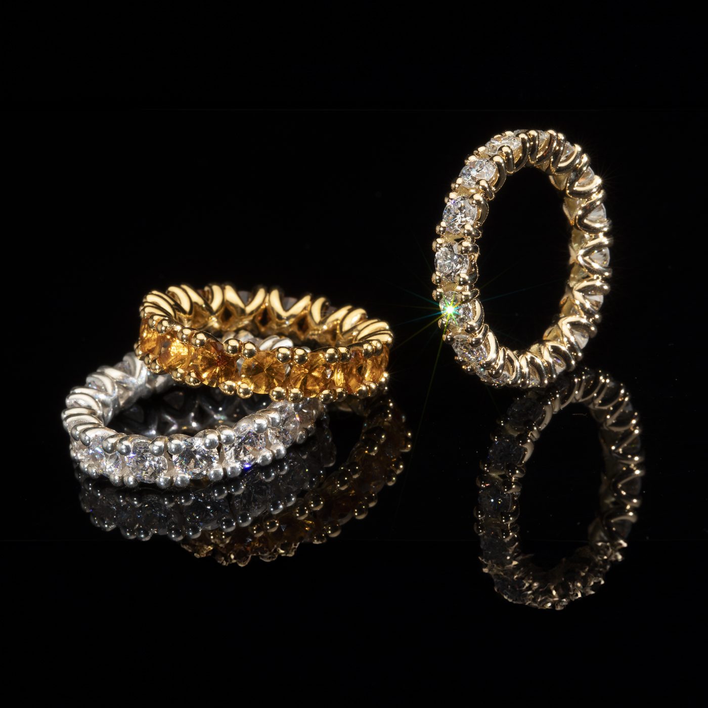 Diamant-Eternity-Ringe in Gelbgold und Weißgold auf schwarzem Grund